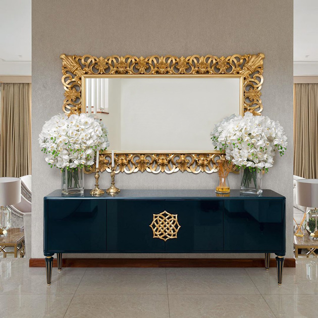 Image Description: Horizontal Decorative Mirror in gilded wood on top of a blue sideboard. 